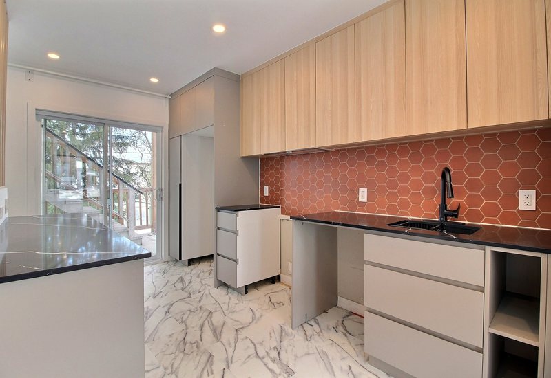 Cuisine installée par IDC rue Saint-André à Montréal : armoires de chêne clair, dosseret hexagonal terracotta et comptoir de quartz noir